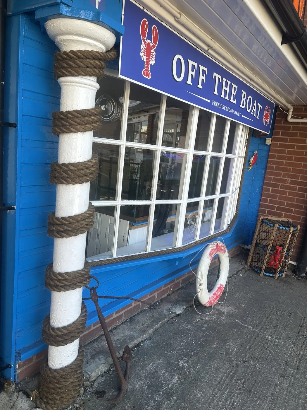 The blue Off The Boat seafood shopfront at The Arches in Hartlepool, with nautical rope around the pillar